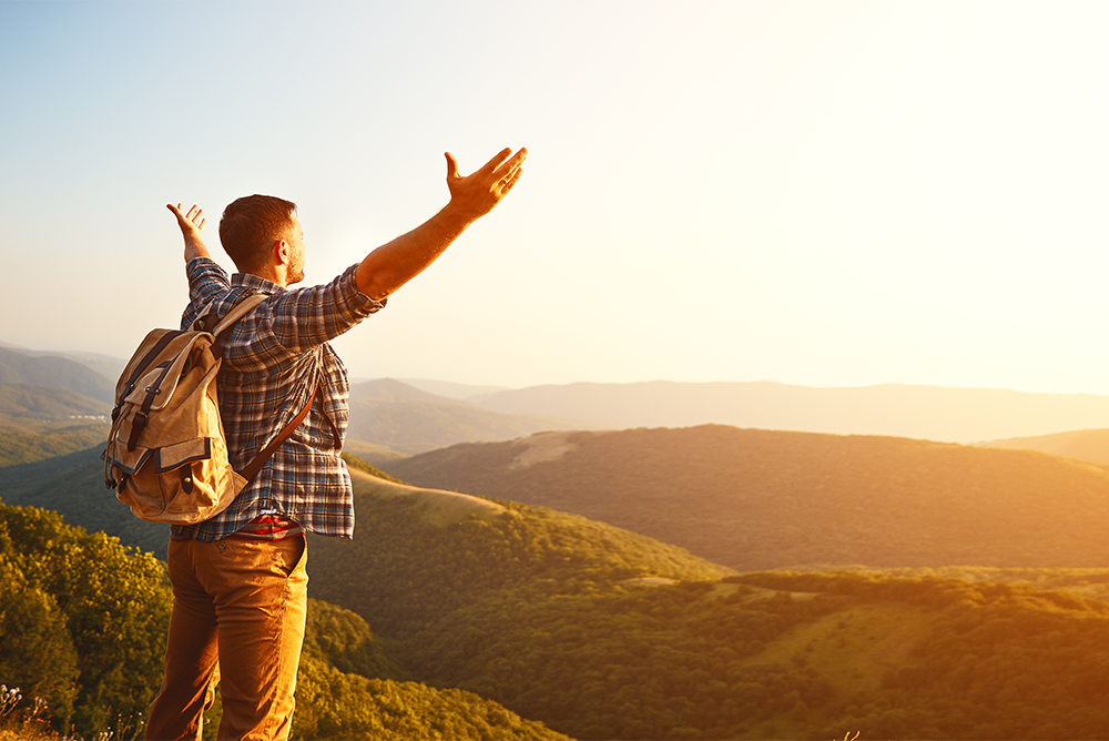 man-standing-on-edge-of-cliff-near-mountains