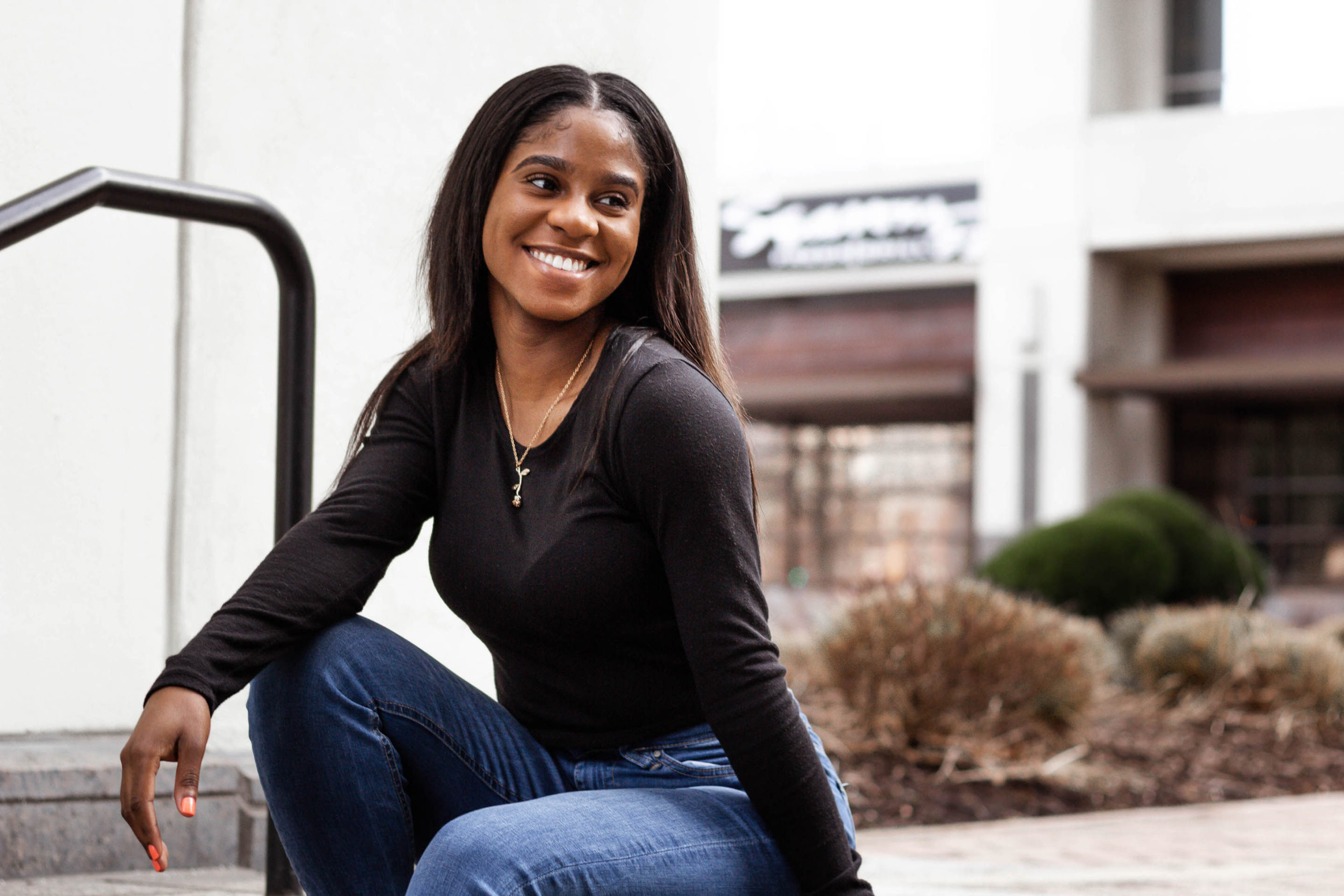 black-woman-sitting-on-steps-outside-smiling-guesthouse