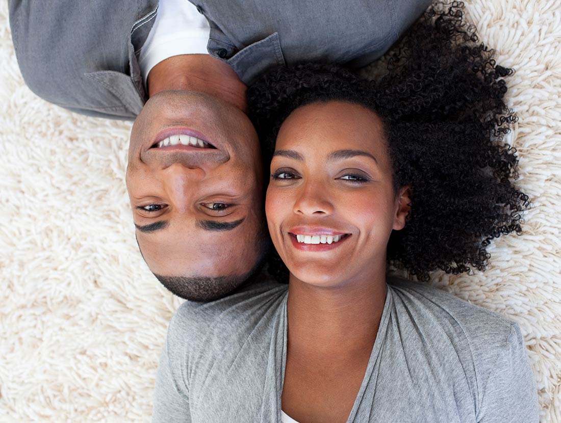 black-man-black-woman-laying-on-rug-smiling-guesthouse