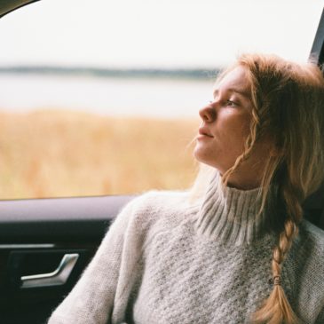 woman looking through car window with a sad look