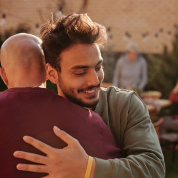 man in long sleeve shirt hugging a family member