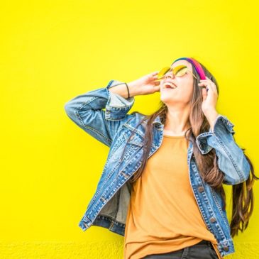 smiling woman looking upright standing against yellow wall