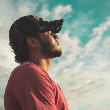 thoughtful man standing against blue sky