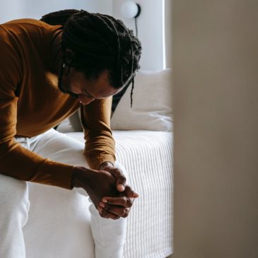 thoughtful man sitting in bed looking down
