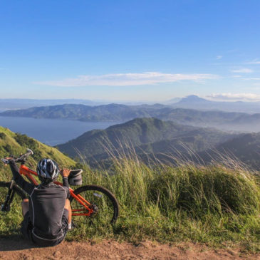 biker sitting on the side of the road against a landscape
