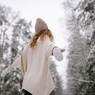 young lady opening arms and looking up against winter landscape