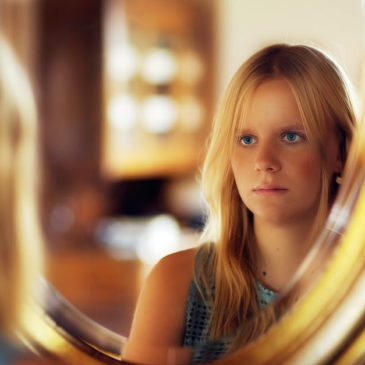 young girl looking at herself through the mirror